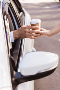 被裁剪的司机购买咖啡在纸杯和坐在车上的形象