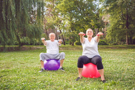 微笑的资深夫妇做健身运动在公园健身球