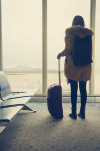 年轻女子在机场，在飞机窗户望