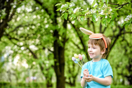 上一天找复活节彩蛋在春天的花园里的小男孩。可爱
