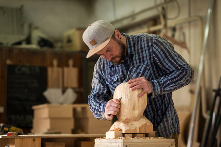 一个木匠的特写, 建筑工人在工作中锯出雕塑从木一个人的头在车间里, 周围有很多工具, 木制, 家具的工作