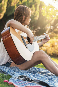 hermosa mujer tocando la guitarra en el parque美丽的女人，在公园里的吉他