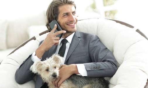 成功的商人持有他的狗和宠物和对智能手机的会谈