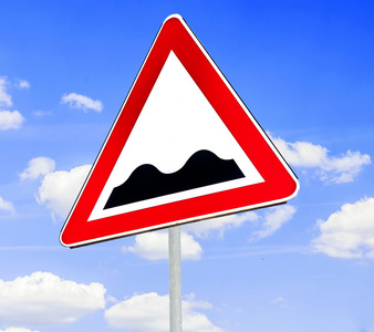 红色和白色三角警告路标与坎坷的道路前方概念在湛蓝的天空背景下的警告