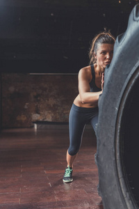 在阁楼的年轻运动妇女与 crossfit 轮