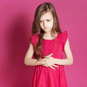 8岁的小女孩在粉红色的中性背景下, 用手做一些情绪化的手势。她有长黑发和穿红色夏天礼服。她脸上的滑稽表情