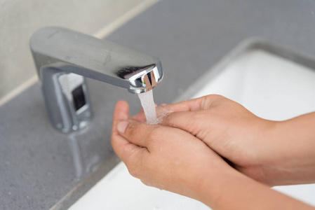 选择焦点妇女洗手用肥皂下水龙头与水在浴室