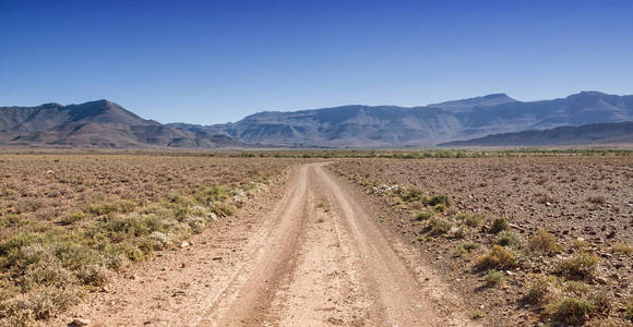 沙漠中的地面公路伸展到地平线上的蓝天背景下, 南部非洲稀树草原