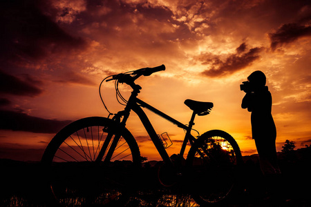 男孩和自行车上日落背景的剪影