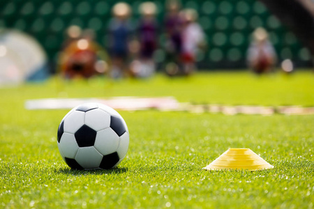运动场上的足球训练设备。足球场和塔盘锥在草地上的音高。年轻球员在后台训练足球