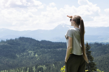 女人站着看着远方。森林和山在背景