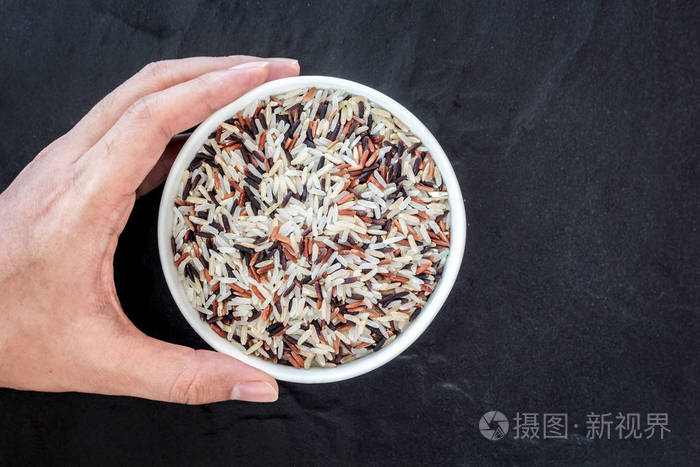 手捧大米在碗上黑色背景
