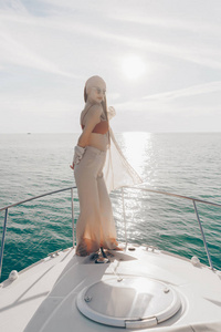 美丽的时尚女孩摆在她的游艇在阳光下, 航行加勒比海