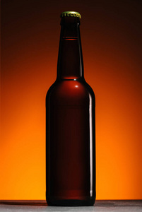 在橙色背景下关闭啤酒瓶的视图