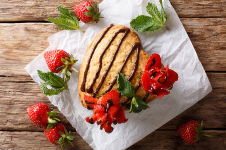 美味的海绵蛋糕在形状的心脏, 装饰与巧克力和草莓玫瑰特写在桌子上。从 abov 的水平顶部视图