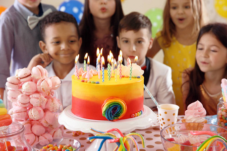 可爱的孩子们在桌上的生日蛋糕上吹蜡烛
