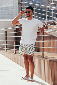 在阳光明媚的夏日, 泳池甲板附近的年轻时尚男士的肖像。生活方式