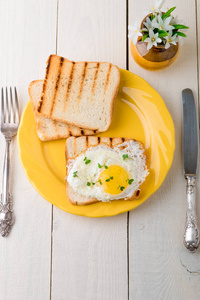 烤面包，鸡蛋黄板附近与花白色木制背景上的花瓶中。健康的早餐。顶视图