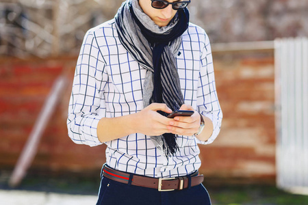时尚的年轻男子在太阳镜与电话走在街上