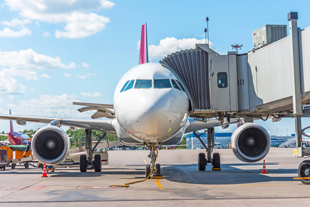 商用客机在机场的停车场用鼻子向前和一个舷梯前视图。飞行的服务和准备