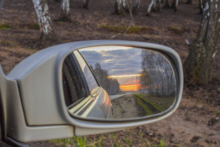 夕阳反射在后视镜里的一辆汽车在公路上。模糊镜头