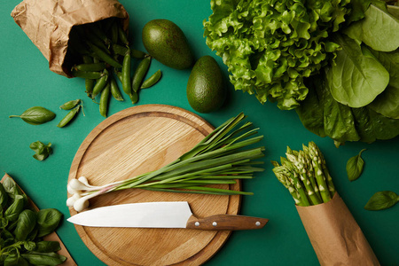 木制切板和刀在绿色表面上的不同熟蔬菜的顶部观图片