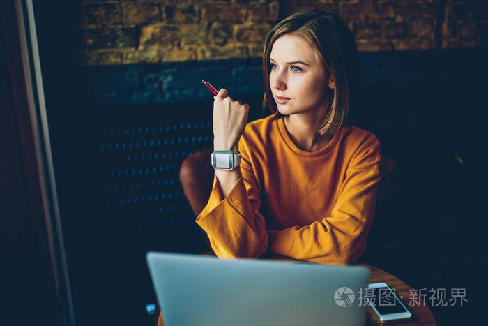 迷人的时尚时髦的女孩与现代 smartwatch 在手上看窗外, 并思考开发