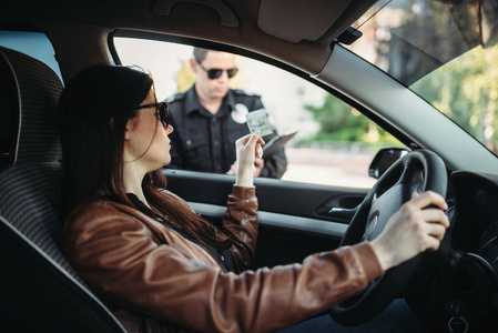 穿制服的男警察给女司机写了一份罚款。法律保护, 汽车交通检查员, 安全控制工作