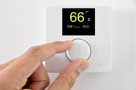 一只手调整温控器数字在华氏在家。家庭自动化