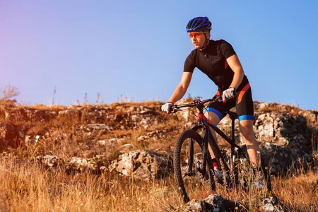 职业自行车手骑自行车在岩石的踪迹。运动员的头盔和墨镜