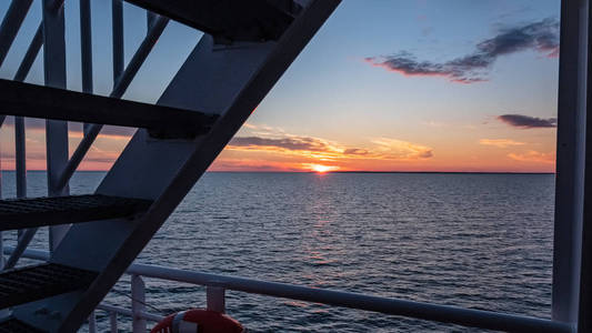 通过船只绳索和金属栏杆看到波罗的海上空的戏剧性的红色日出