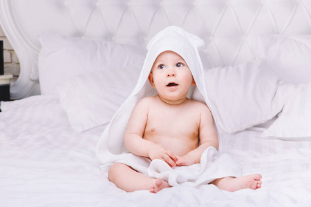 婴儿躺在床上的白毛巾 adorably。快乐的童年和医疗保健概念