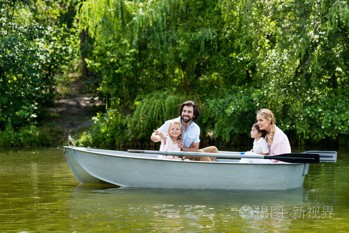 年轻的家庭花时间一起在河上的小船在公园和看远