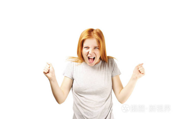 美丽的年轻女子 自然红发与握紧拳头和可怕的愤怒的面部表情.