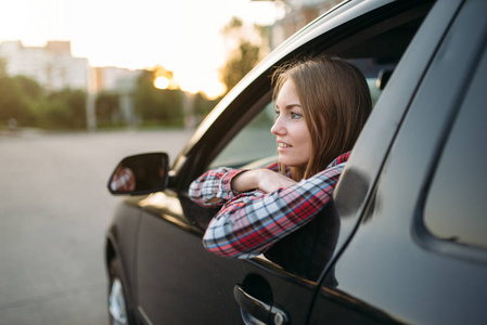 微笑的女性司机初学者从车窗外看。妇女在车, 驾驶汽车概念