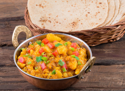 印度菜辣煎菠菜也知道土豆炒, 土豆咖喱, 菠菜马萨拉或铝马萨拉服务与印度面包, 印度或烤薄饼在木桌上