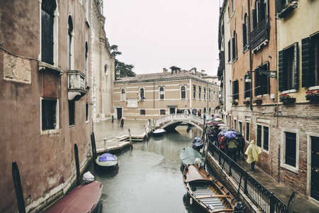 游客在大雨中把雨伞放在一条小运河里。威尼斯, 意大利