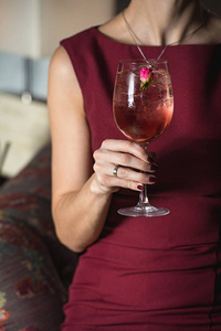 女人拥有放松酒精粉红色鸡尾酒顶上的一朵玫瑰
