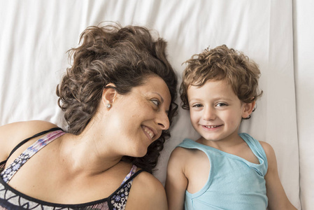 一个女人和她的儿子在床上玩耍, 示意