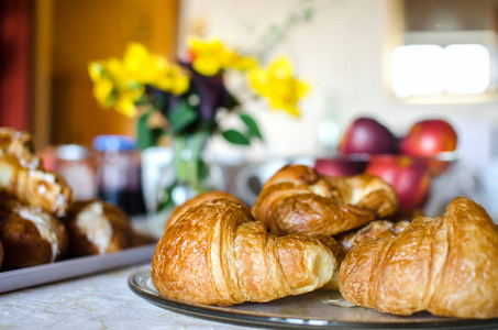 早餐桌上有鲜花和水果的新鲜法式羊角面包。传统