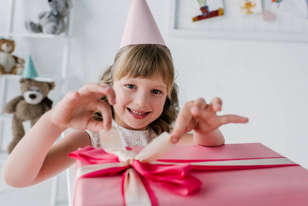 快乐的孩子在锥体打开生日礼物盒和看照相机