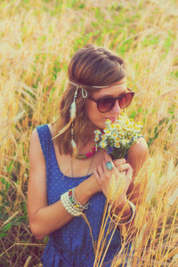 美丽的妇女在太阳镜持有野花花束, 而放松在大麦草甸