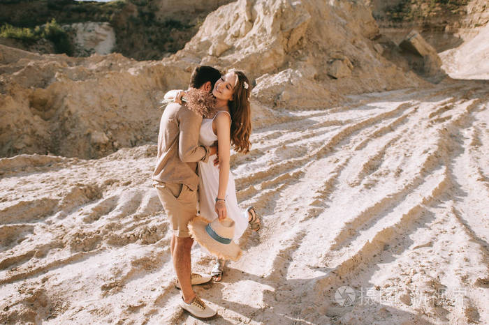 时尚的男朋友拥抱和亲吻他美丽的女朋友在沙峡谷