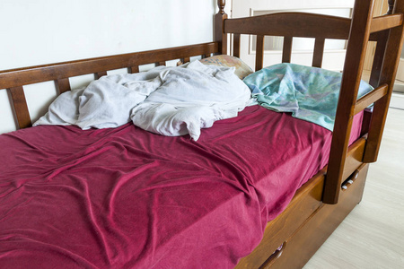 皱巴巴的红色和白色床上用品和丸未经修筑的弯弯曲曲的儿童床