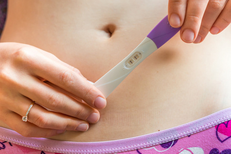怀孕的妇女抱着积极的怀孕测试