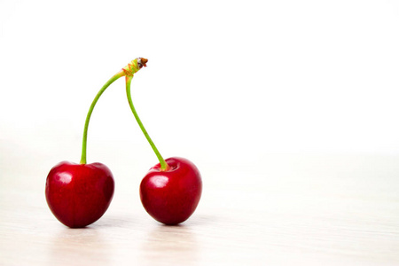 健康饮食和饮食概念两个樱桃特写。樱桃木和白色背景。Copyspace