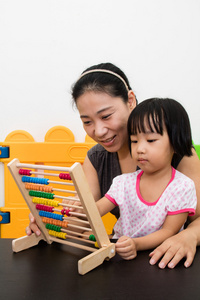 亚洲的中国小女孩和母亲玩算盘在一起