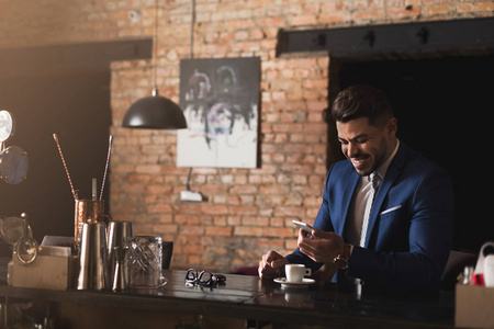微笑的商人使用智能手机在酒吧