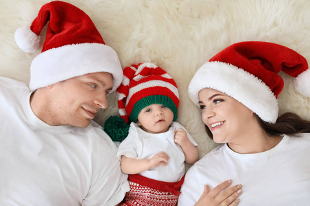 快乐夫妇与婴孩在圣诞节帽子在模糊的地毯上, 顶部视图