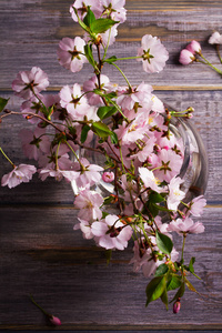 粉红色的花朵在花瓶放在木制的灰色背景。春天开花。鲜花花束